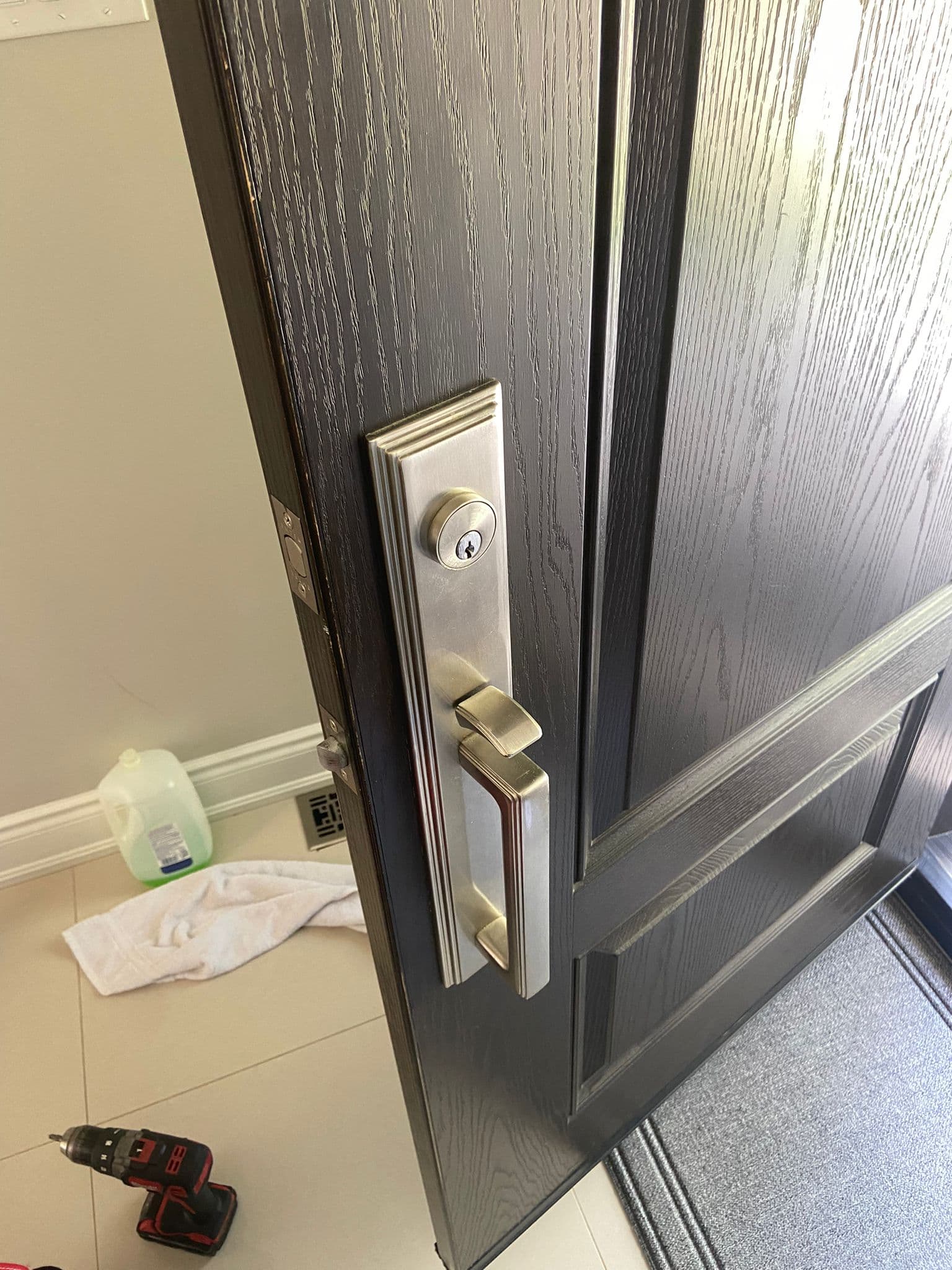 Brushed nickel door handle and lockset mounted on a dark wood-grained door, slightly ajar.